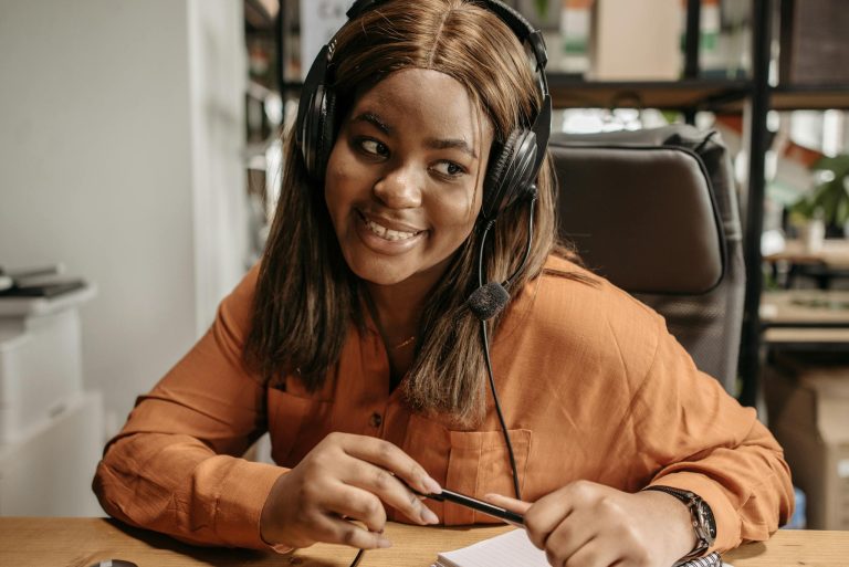 A cheerful customer support agent with a headset provides assistance in an office setting.